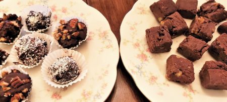 Two round white plates; one holding various chocolate truffles and the other chocolate brownies