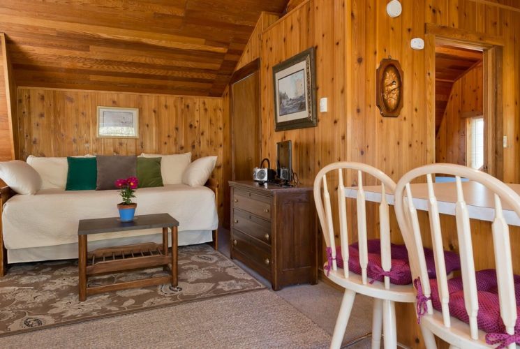 Sitting area of a suite with a daybed, coffee table, and wood dresser with TV