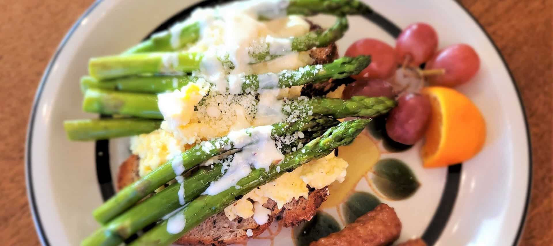 Breakfast plate with orange, grapes and eggs on toast with bright green asparagus