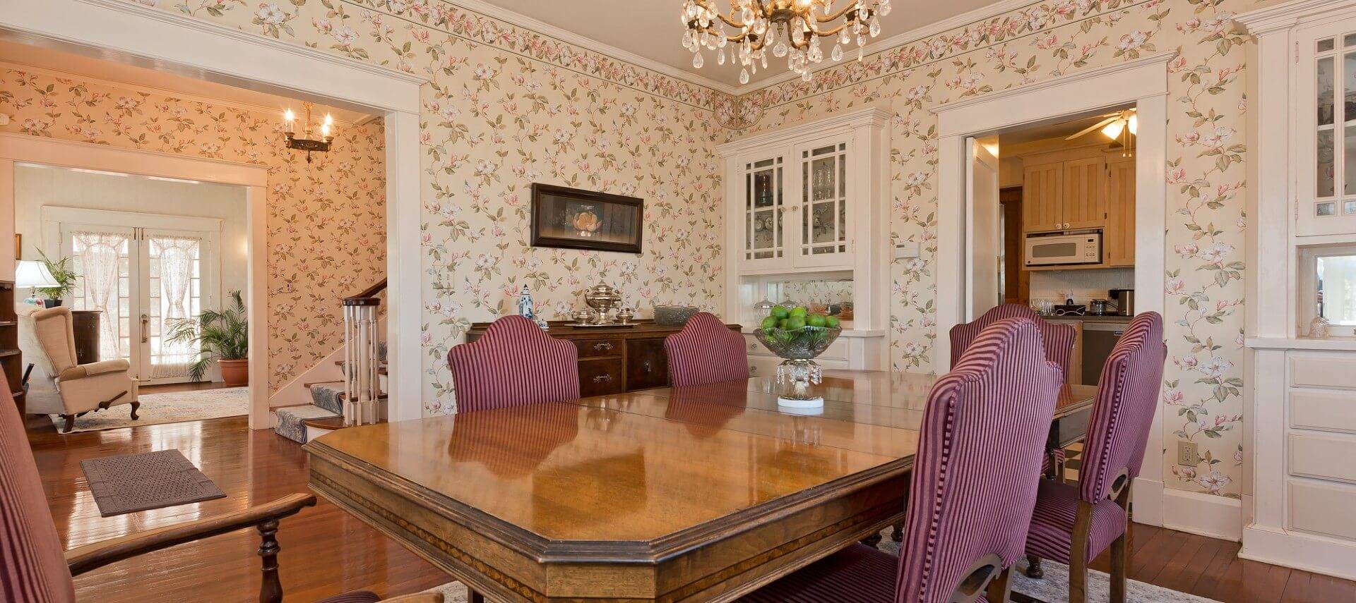 Large open dining room with table and chairs, white built-ins and doorways into kitchen and living room